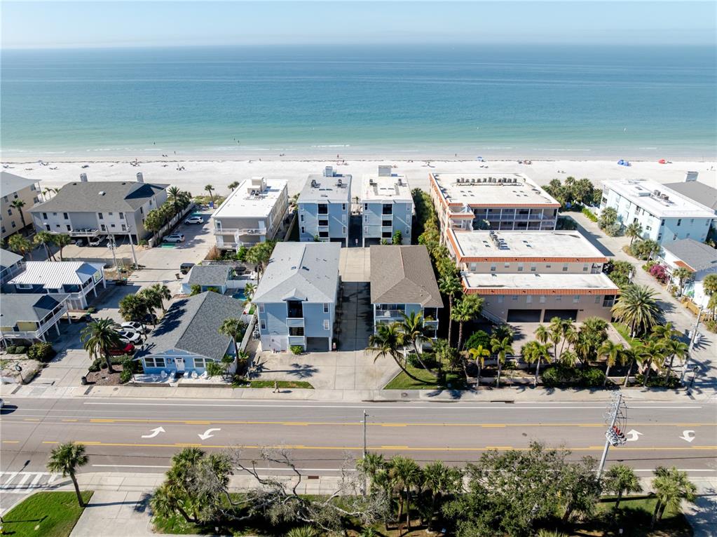An aerial view shows several multi-story beach houses and apartment buildings situated near the ocean — 1904 GULF BOULEVARD UNIT D, INDIAN ROCKS BEACH, FL