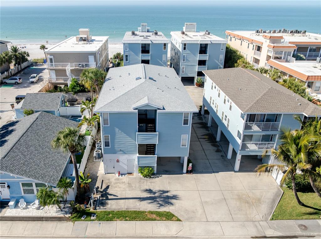 An aerial view shows a light blue multi-story house near a sandy beach and ocean — 1904 GULF BOULEVARD UNIT D, INDIAN ROCKS BEACH, FL