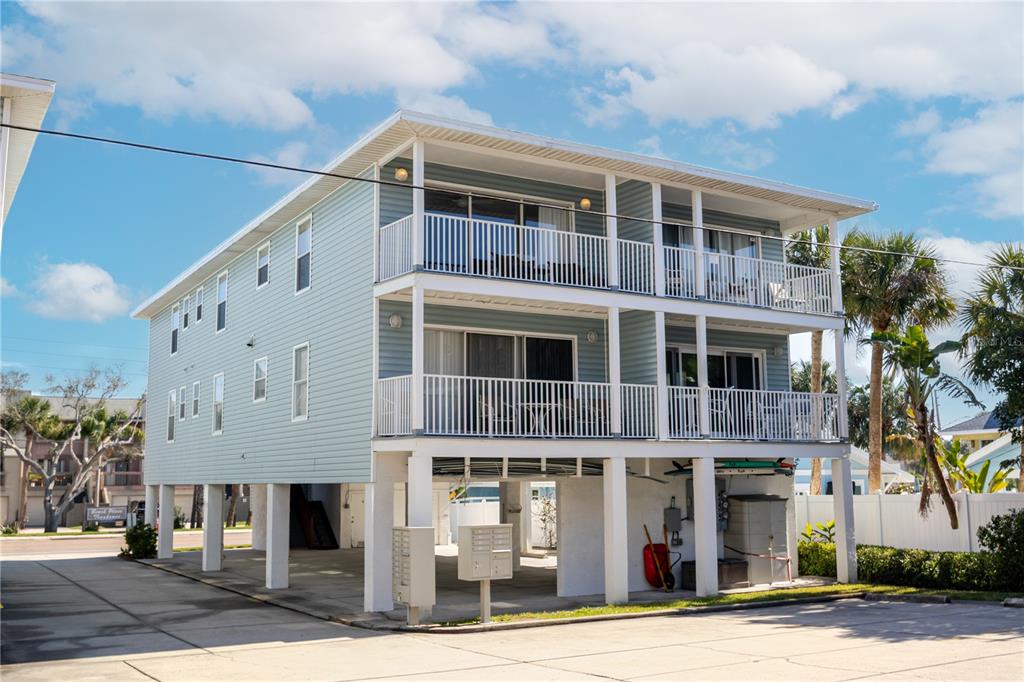 A light blue, two-story stilt house with white railings and a concrete parking area underneath — 1904 GULF BOULEVARD UNIT D, INDIAN ROCKS BEACH, FL