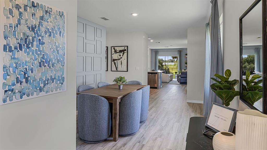 A dining area with a wooden table and blue chairs leads into a living room — 4052 GIORGIO DRIVE, WINTER HAVEN, FL
