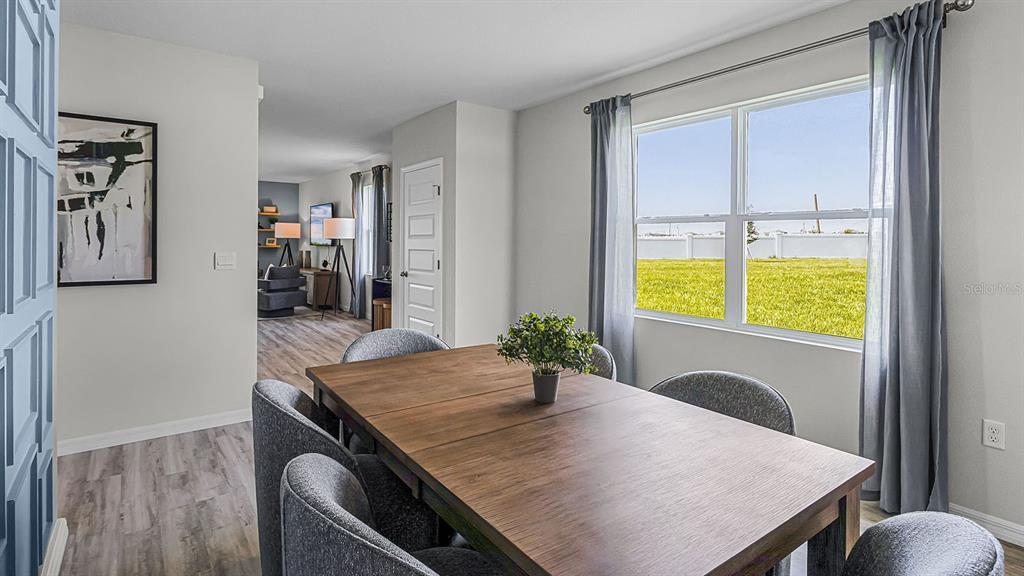 A dining room with a wooden table, grey chairs, and a window overlooking a field — 4052 GIORGIO DRIVE, WINTER HAVEN, FL