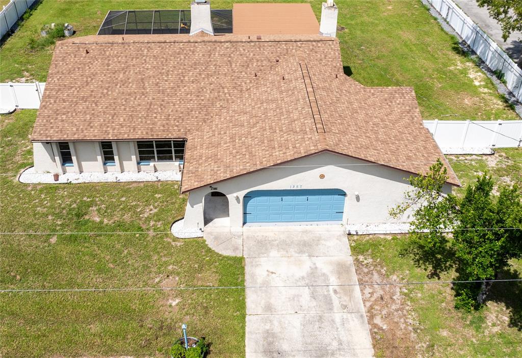An aerial view shows a single-story house with a brown shingled roof and blue garage — 1257 FINLAND DRIVE, SPRING HILL, FL
