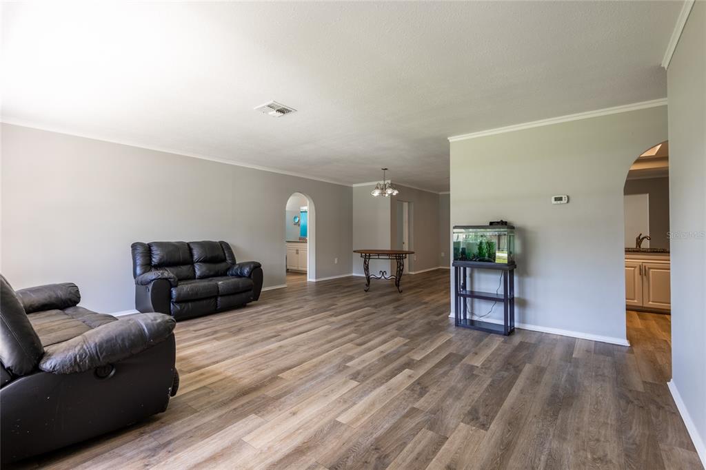 A living room features wood-look flooring, light gray walls, two black sofas, and an aquarium — 1257 FINLAND DRIVE, SPRING HILL, FL
