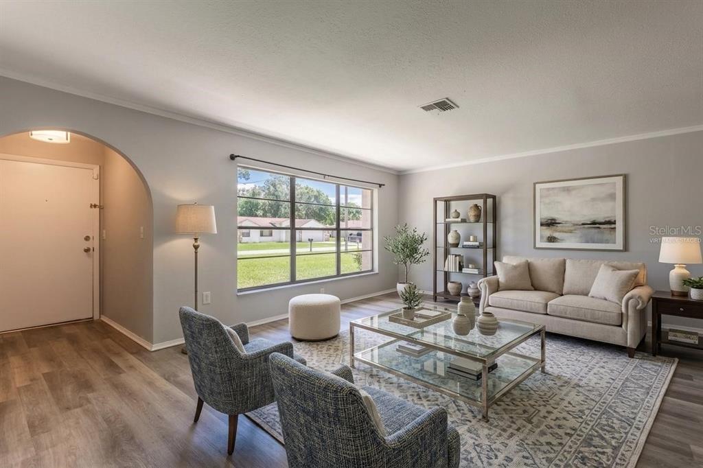 A living room features light gray walls, wood-look flooring, two black leather sofas, and a large window — 1257 FINLAND DRIVE, SPRING HILL, FL