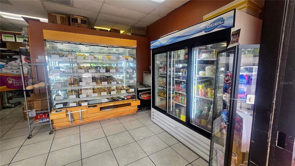 A bakery interior features a large glass display case for pastries and a refrigerated cooler — 1450 SKIPPER ROAD, TAMPA, FL