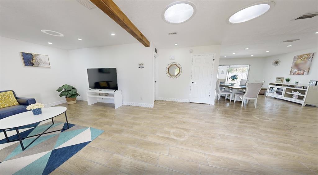 A living and dining area features wood-look tile flooring, a wooden ceiling beam, and skylights — 8622 BAYLOR CIRCLE, ORLANDO, FL