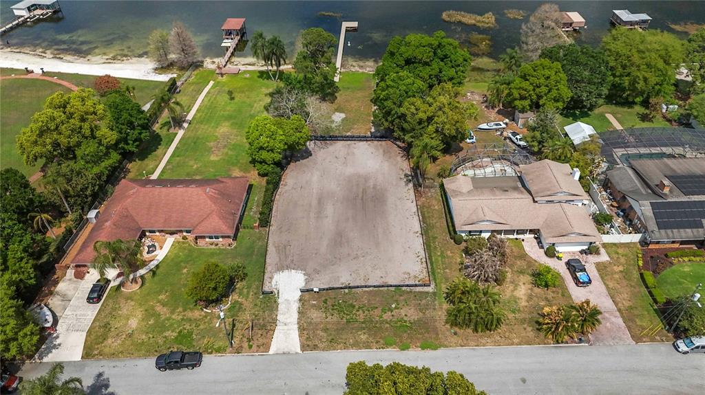 An aerial view shows a vacant, rectangular waterfront lot with a dock extending into the lake — 2815 TRENTWOOD BOULEVARD, BELLE ISLE, FL