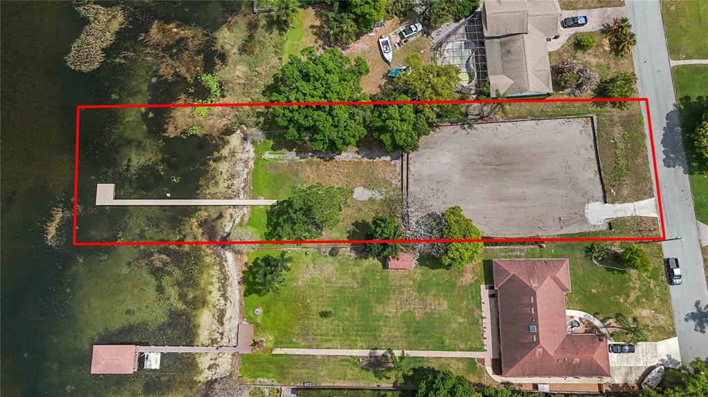 An aerial view shows a grassy waterfront property with a long dock and boat house — 2815 TRENTWOOD BOULEVARD, BELLE ISLE, FL