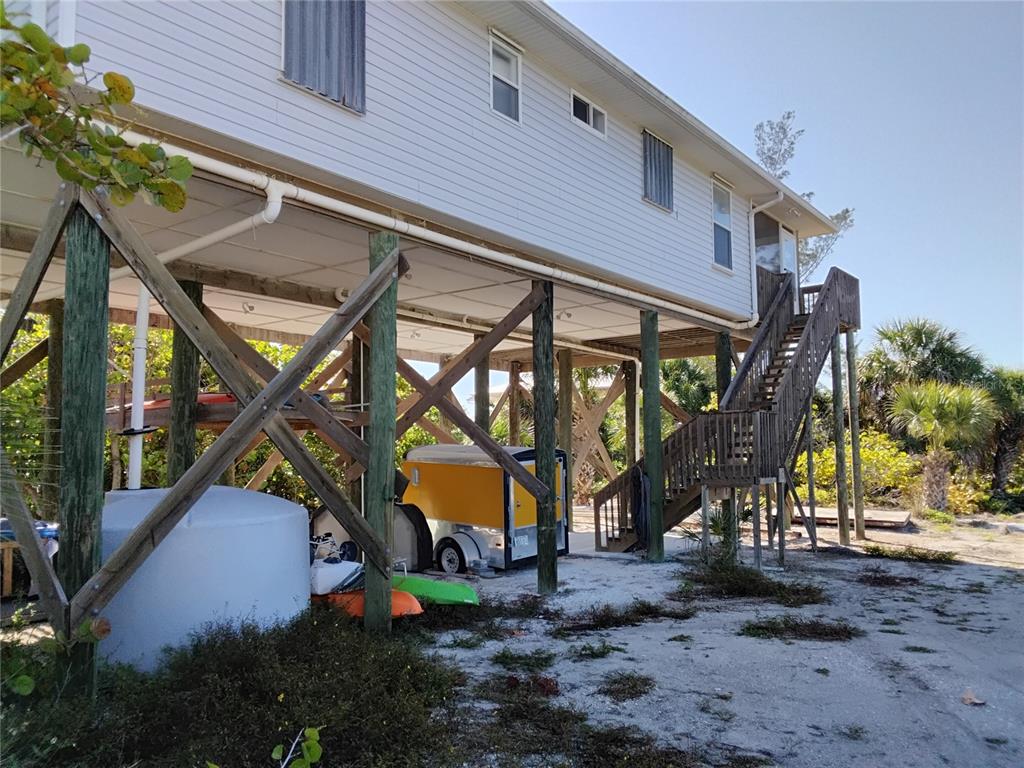 An elevated house on wooden pilings with a staircase leading to the main level — 91 GASPARILLA WAY, PLACIDA, FL