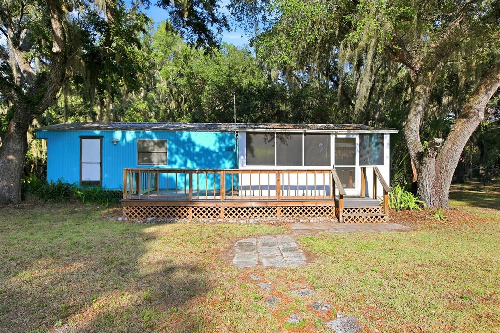 A light yellow mobile home features a screened-in porch and a gravel driveway — 3348 OMEC STREET, LAKE WALES, FL