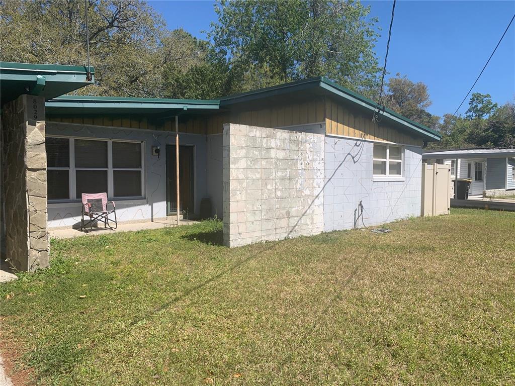 A single-story house features a light blue exterior, a stone pillar, and a concrete block wall — 8029 CHATEAU DRIVE S, JACKSONVILLE, FL