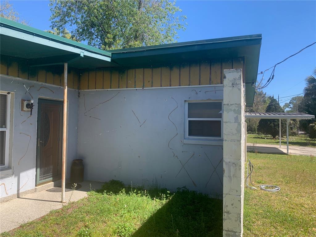 The exterior of a house features a blue wall with cracks, a door, and a window — 8029 CHATEAU DRIVE S, JACKSONVILLE, FL