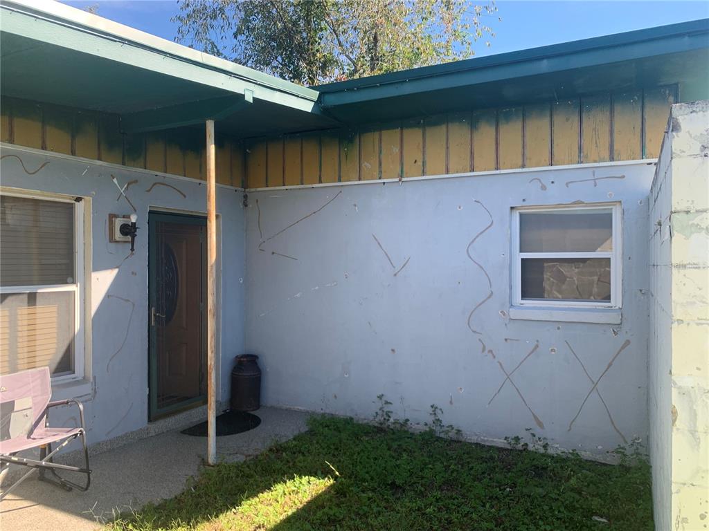 An exterior view of a house entrance with a patio, light blue walls, and siding — 8029 CHATEAU DRIVE S, JACKSONVILLE, FL