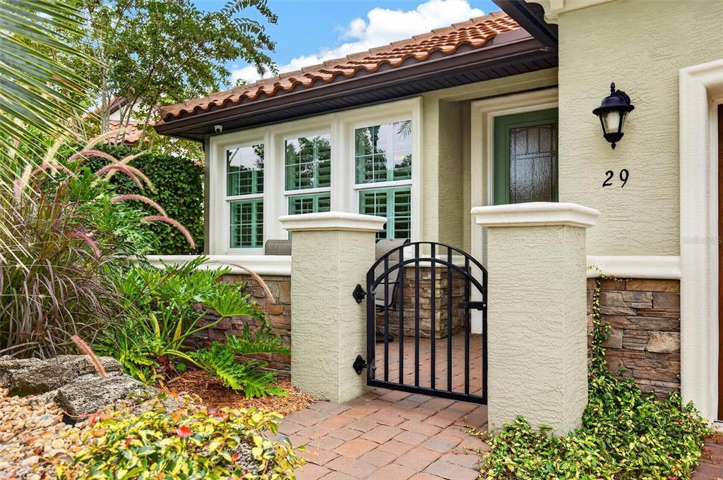 A gated courtyard entrance features a stone facade, a black metal gate, and windows — 29 APIAN WAY, ORMOND BEACH, FL