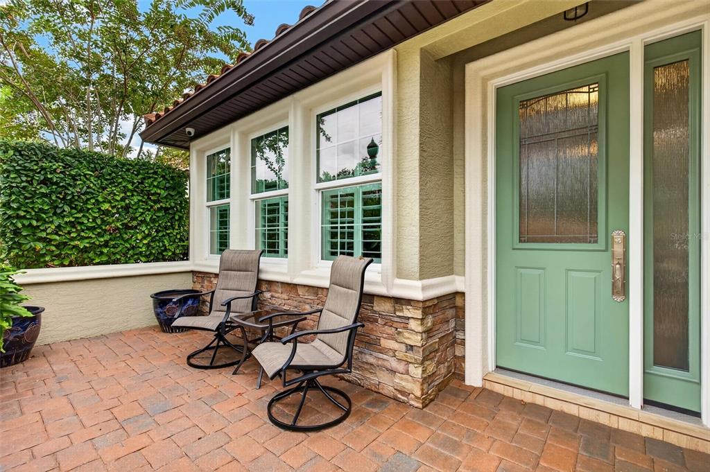 A patio with two chairs and a table sits outside a house with a green door — 29 APIAN WAY, ORMOND BEACH, FL