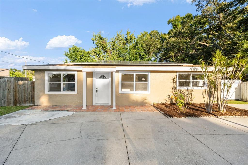 A single-story tan house with a concrete driveway and solar panels on the roof — 2913 MCINTOSH ROAD, SARASOTA, FL