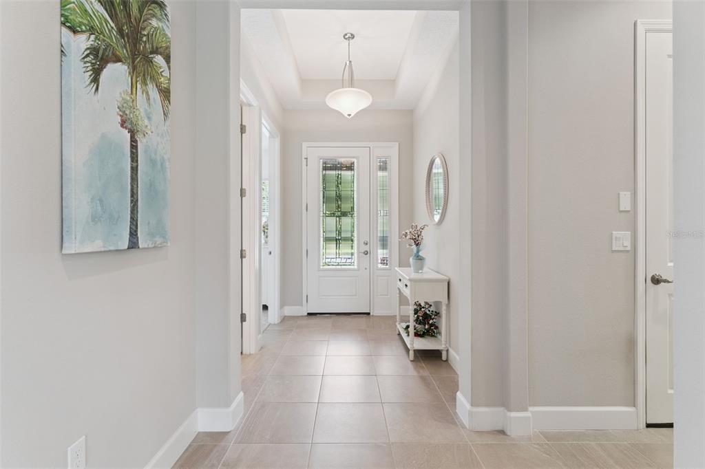 A bright entryway features light tile flooring, a white front door, and a tray ceiling — 1649 VICTORIA GARDENS DRIVE, DELAND, FL