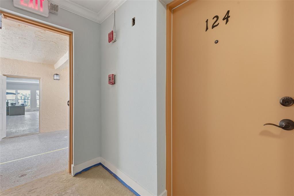 A hallway shows a tan door labeled 124 next to an open doorway leading into an office — 8901 BLIND PASS ROAD UNIT 124, ST PETE BEACH, FL