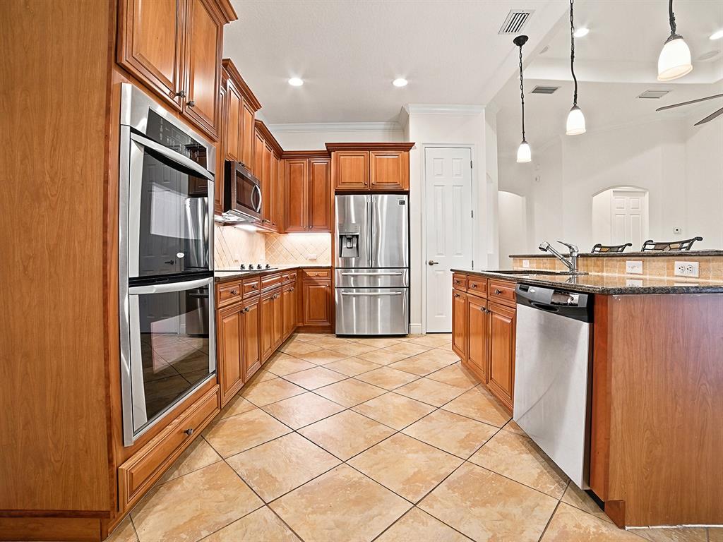 A kitchen island with wood cabinets and a granite countertop sits on a tiled floor — 1404 CARING COURT, MAITLAND, FL