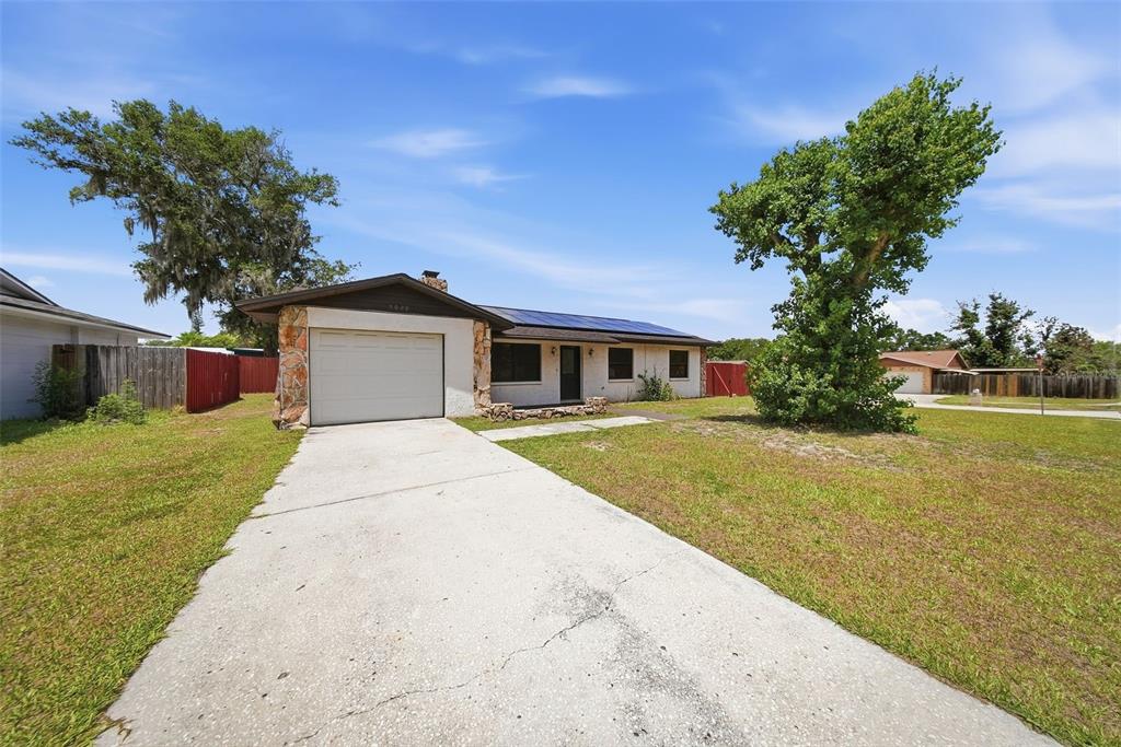 A single-story house with a white garage, stone accents, and solar panels on the roof — 5020 PINE STREET, SEFFNER, FL