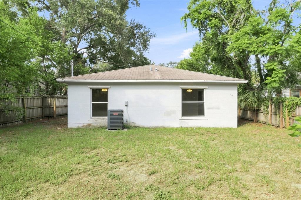 The exterior rear view of a single-story white brick house with a fenced backyard — 2324 OAKDALE STREET S, ST PETERSBURG, FL