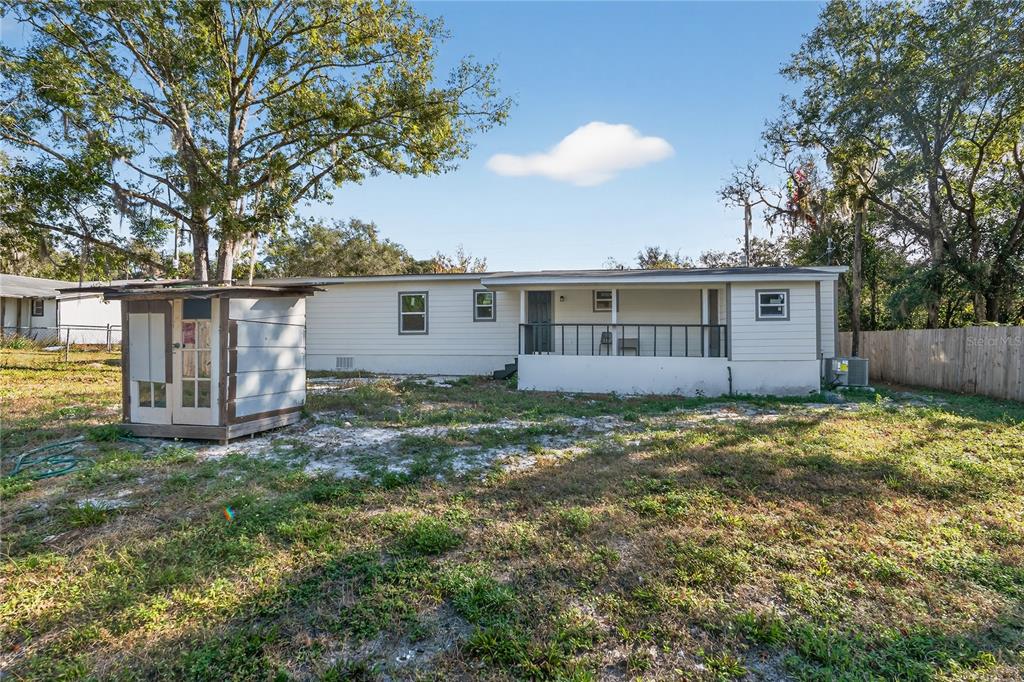 A single-story house with a covered porch and a small detached shed in the yard — 40415 COUNTRY ROAD, EUSTIS, FL