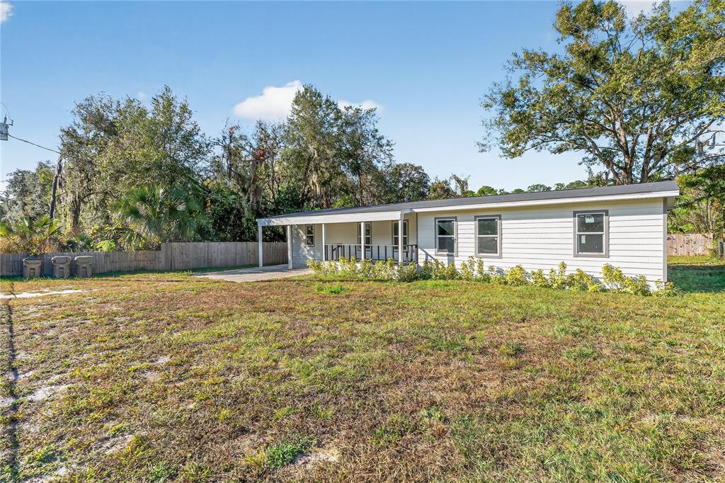 A single-story house with white siding and a covered porch sits on a grassy lot — 40415 COUNTRY ROAD, EUSTIS, FL