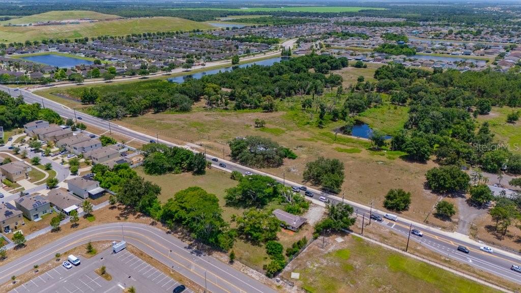 An aerial view shows a residential neighborhood, a large undeveloped lot, and a nearby road — 10912 672 HIGHWAY, RIVERVIEW, FL