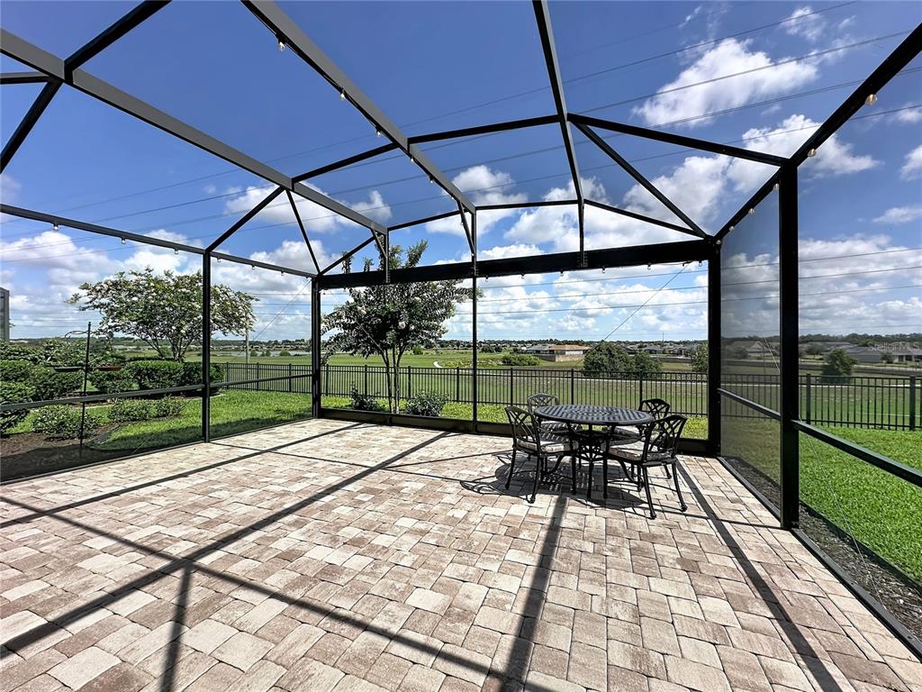 A screened-in patio features a paver floor, a dining set, and views of a grassy field — 164 SILVER MAPLE ROAD, GROVELAND, FL