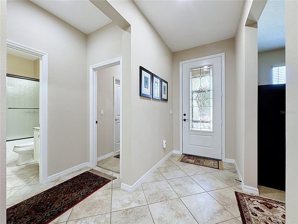 A tiled entryway features a white front door with glass panels and two interior doorways — 164 SILVER MAPLE ROAD, GROVELAND, FL