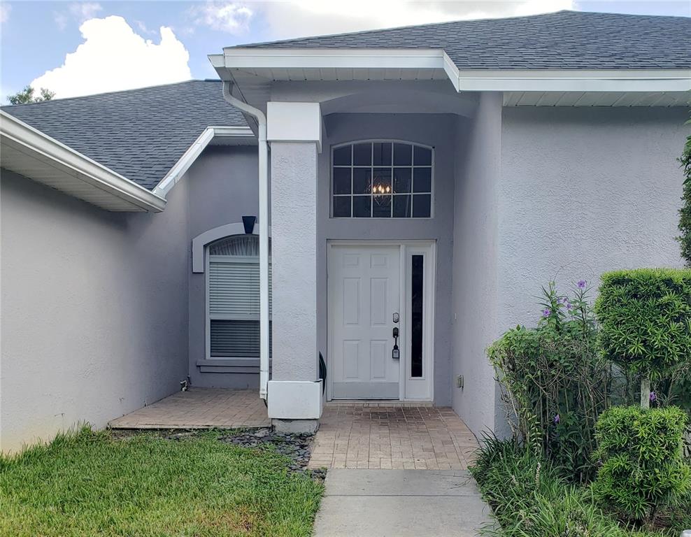 The exterior of a gray house features a white front door and a paved walkway — 3011 PARTRIDGE POINT TRAIL, VALRICO, FL