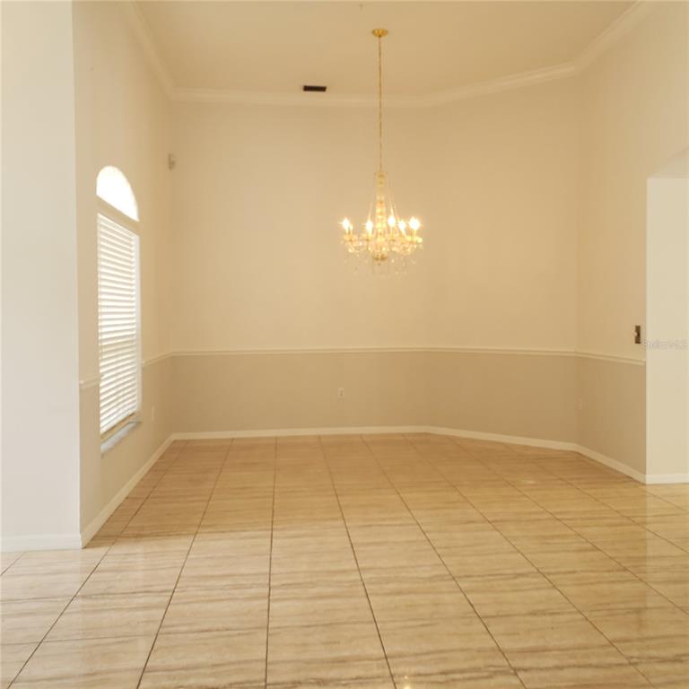 An empty dining room features tile flooring, a crystal chandelier, and two-toned wall paint — 3011 PARTRIDGE POINT TRAIL, VALRICO, FL