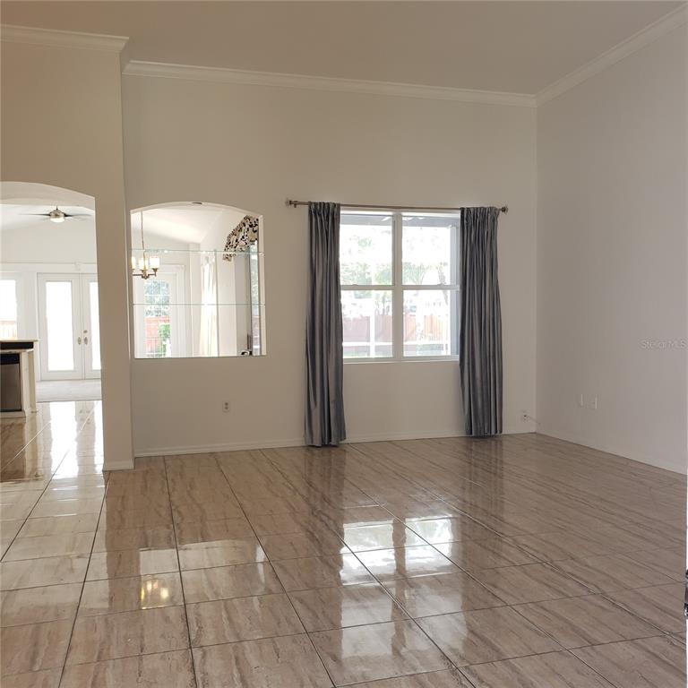 A bright living room features large windows with grey curtains and light-colored tile flooring — 3011 PARTRIDGE POINT TRAIL, VALRICO, FL
