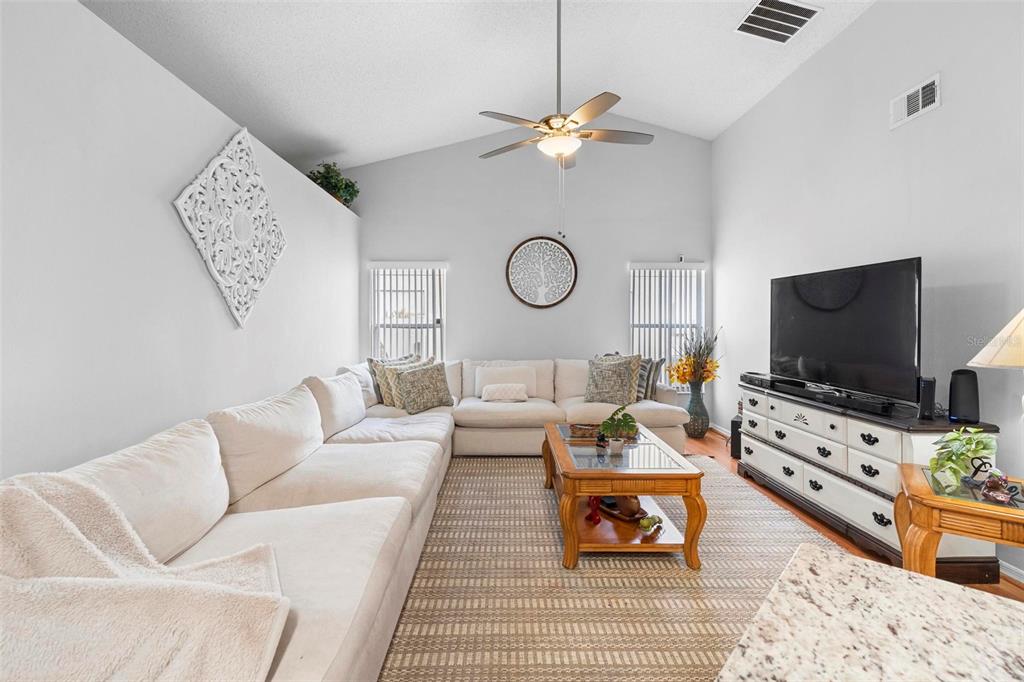 A living room features a large white sectional sofa, a wooden coffee table, and vaulted ceilings — 12512 TILLINGHAM COURT, ORLANDO, FL