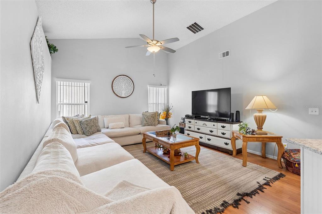 A living room features a large sectional sofa, a wooden coffee table, and a television console — 12512 TILLINGHAM COURT, ORLANDO, FL