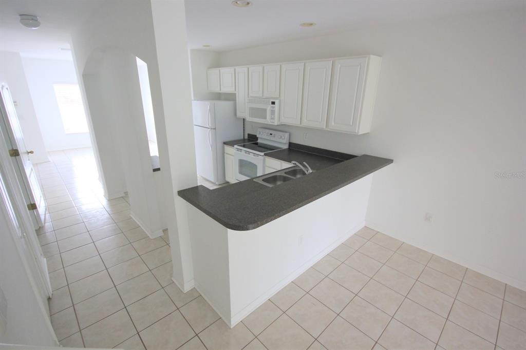 A kitchen with white cabinets, dark countertops, and tile flooring viewed from an elevated angle — 15643 STABLE RUN DRIVE, SPRING HILL, FL