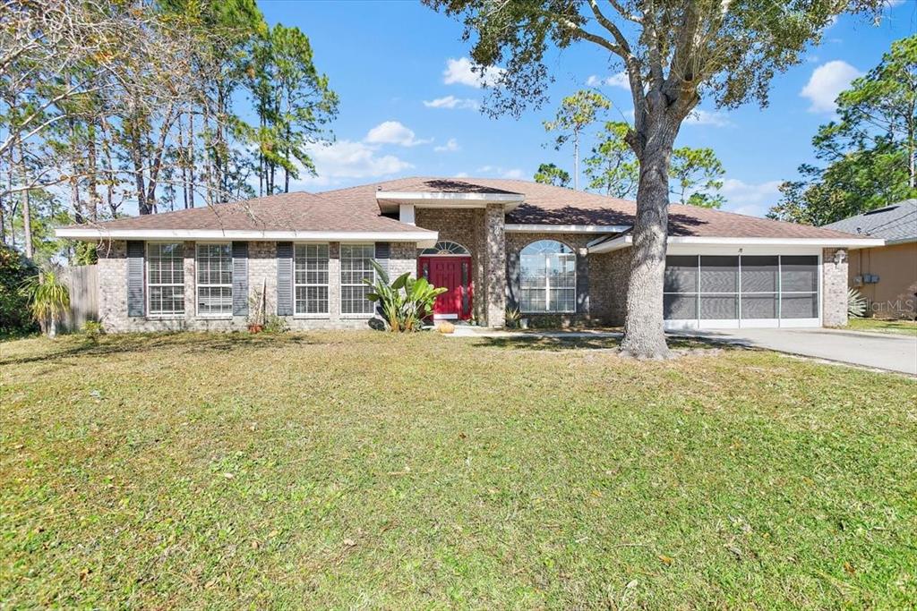 A single-story brick house with a red front door and a screened-in garage — 38 RED MILL DRIVE, PALM COAST, FL
