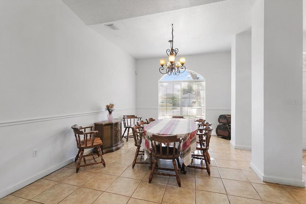 A dining room features tile flooring, a chandelier, and a table with wooden chairs — 38 RED MILL DRIVE, PALM COAST, FL