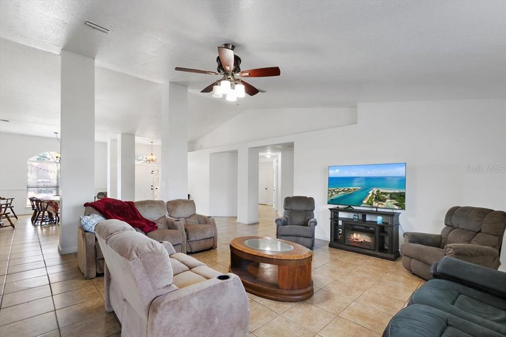 A living room features tile flooring, a ceiling fan, and a television on a stand — 38 RED MILL DRIVE, PALM COAST, FL