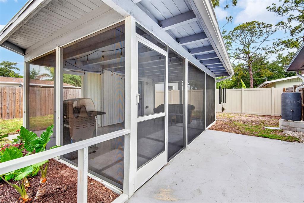 A white, single-story house with a gray gable roof and a red-flowering bush outside — 916 PATTISON AVENUE, SARASOTA, FL