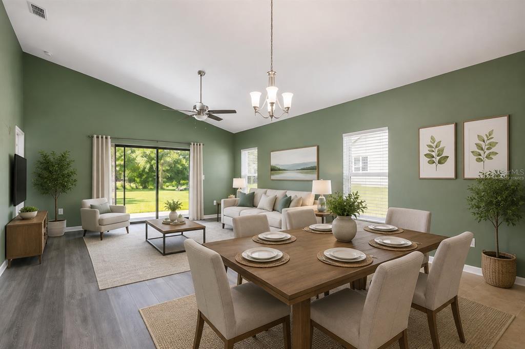 An open-concept living and dining area with green walls, vaulted ceilings, and wood-look flooring — 5343 RADIANCE COURT, COCOA, FL