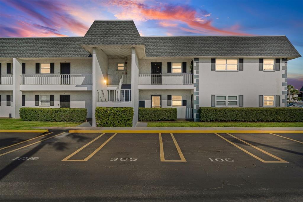 A covered exterior walkway features two dark metal security doors and textured white stucco walls — 4705 5TH STREET W UNIT 305, BRADENTON, FL