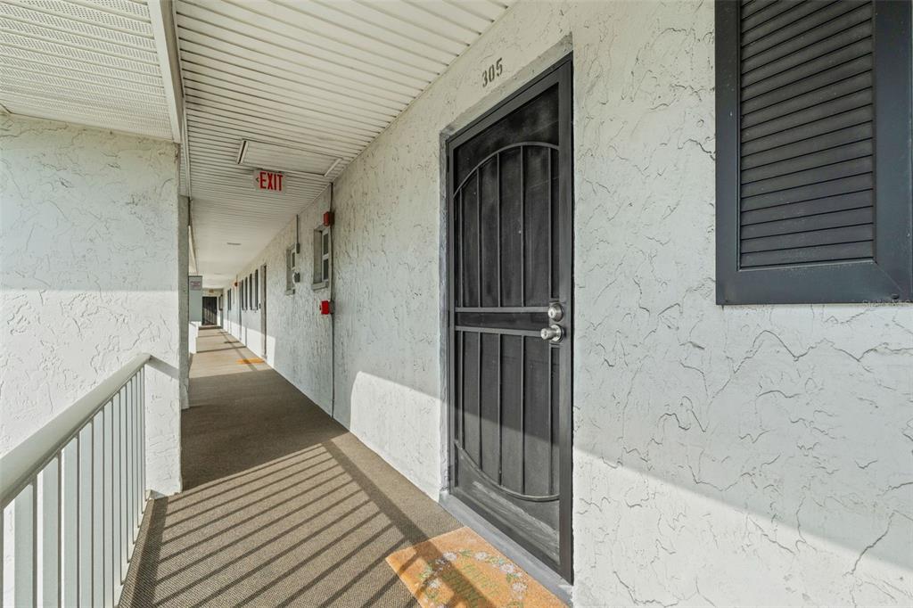 An entryway features a white door, tiled floor, a black console table, and framed artwork — 4705 5TH STREET W UNIT 305, BRADENTON, FL