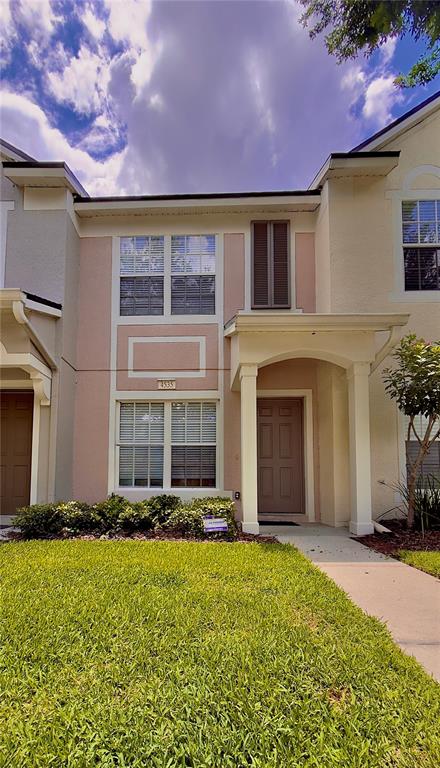 A two-story townhouse exterior features a tan facade, a covered entryway, and a front lawn — 4535 KENNEWICK PLACE, RIVERVIEW, FL