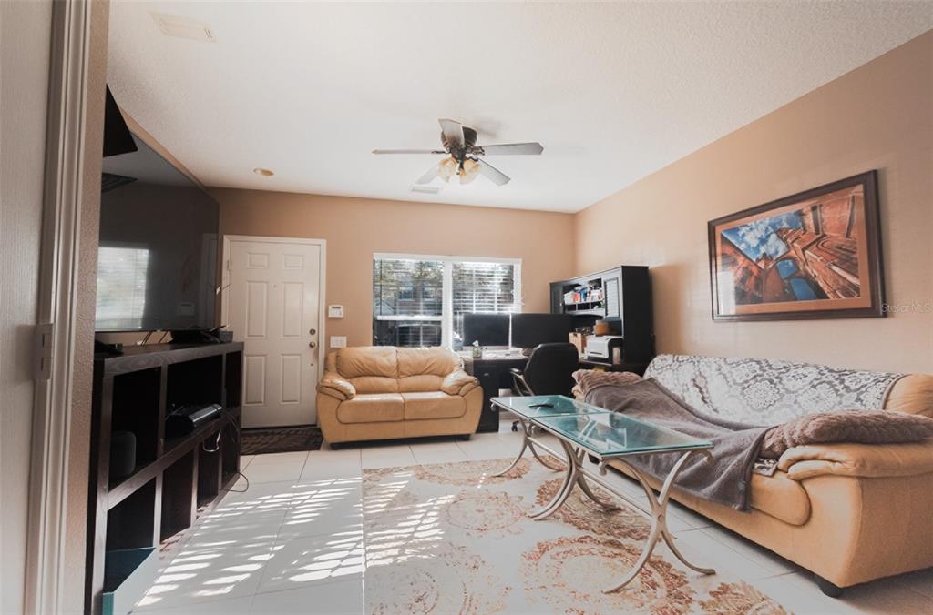A living room features tan walls, tile flooring, a ceiling fan, and two leather sofas — 4535 KENNEWICK PLACE, RIVERVIEW, FL
