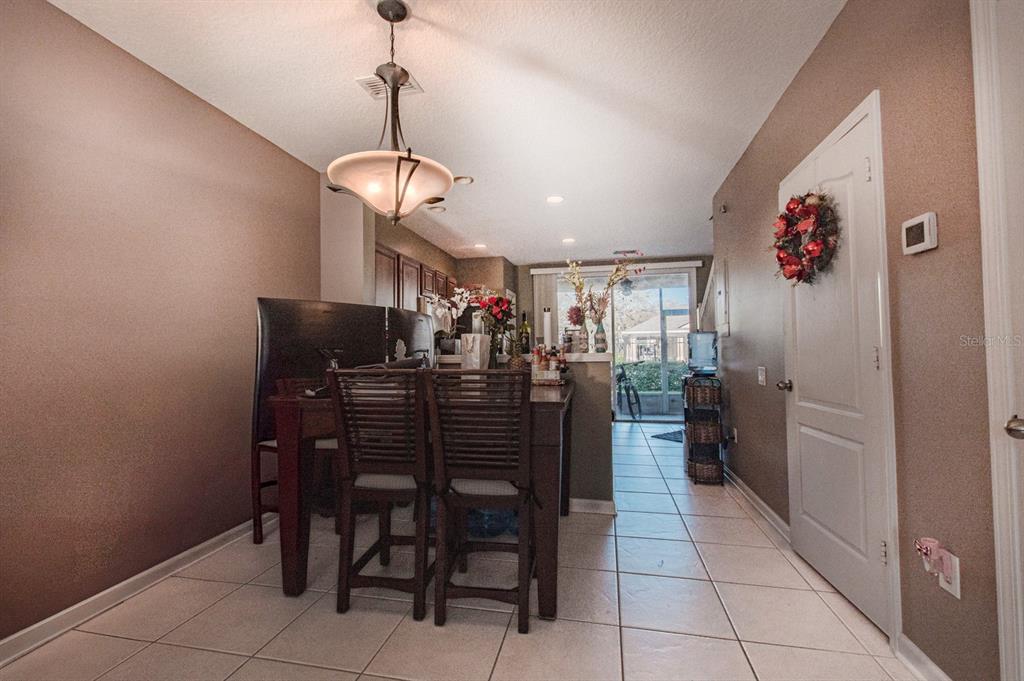 A dining area with a wooden table, slatted chairs, tile flooring, and a hanging light fixture — 4535 KENNEWICK PLACE, RIVERVIEW, FL