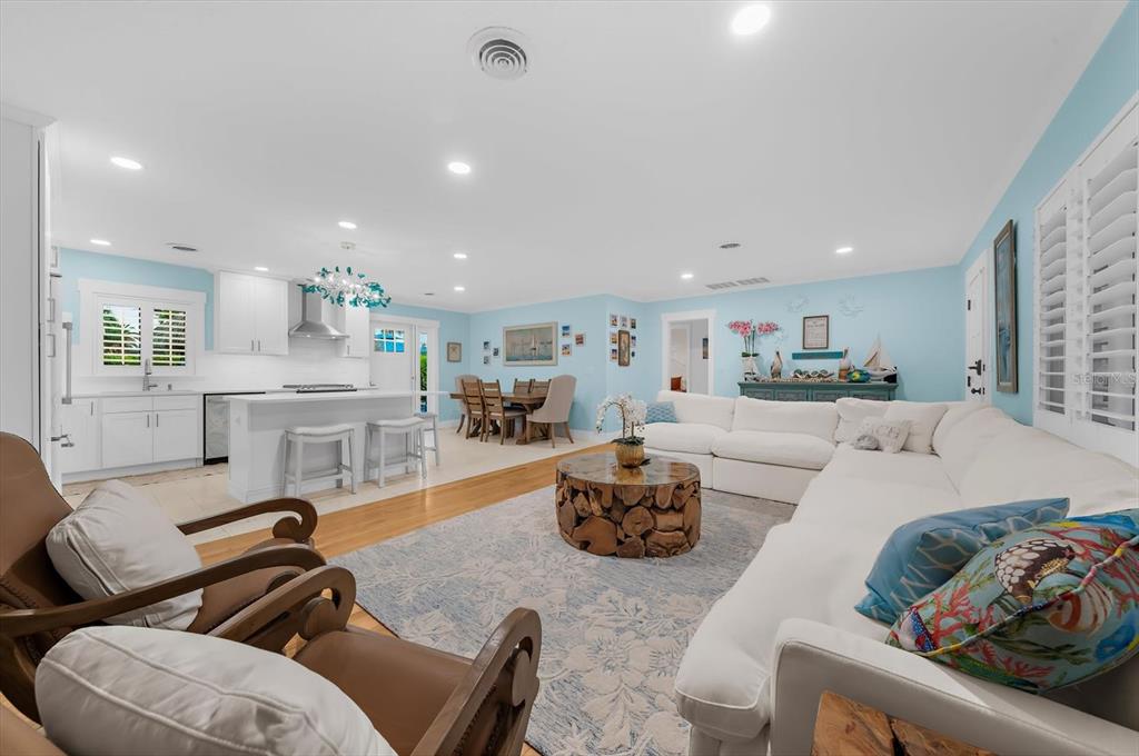 An open-concept living room and kitchen feature light blue walls, white cabinetry, and wood flooring — 751 MANDALAY AVENUE, CLEARWATER BEACH, FL