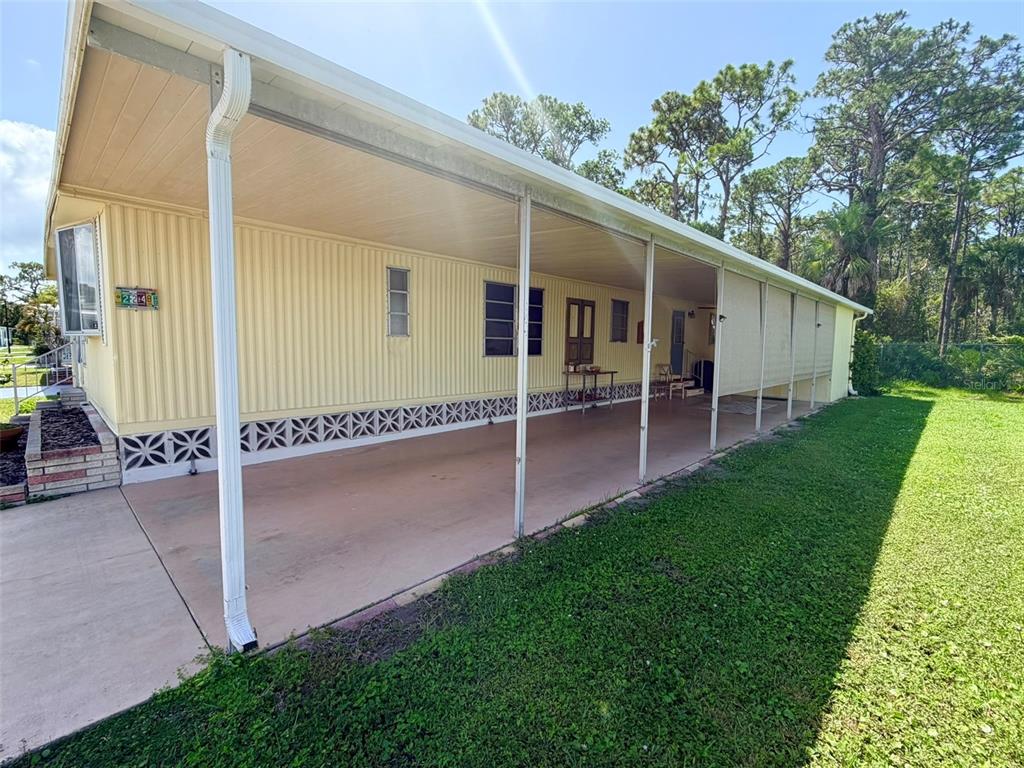 A yellow mobile home features a long covered carport and a concrete driveway — 2248 CA D ORO DRIVE, SARASOTA, FL