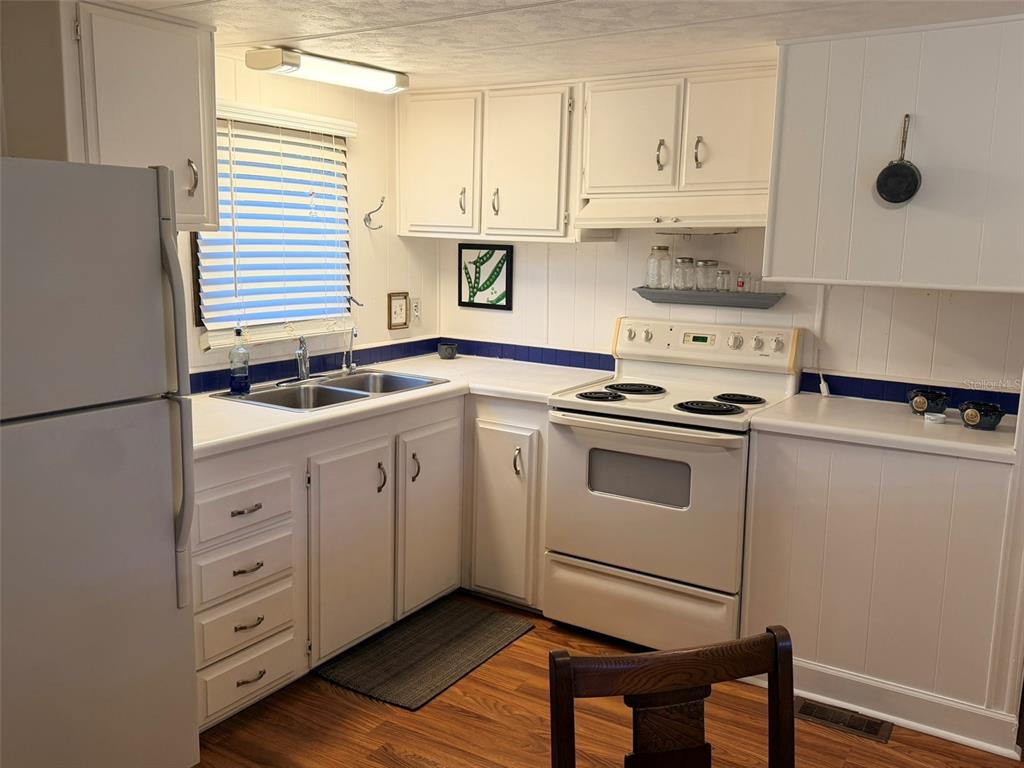 A kitchen with white cabinets, a white stove, a double sink, and blue tile backsplash — 2248 CA D ORO DRIVE, SARASOTA, FL