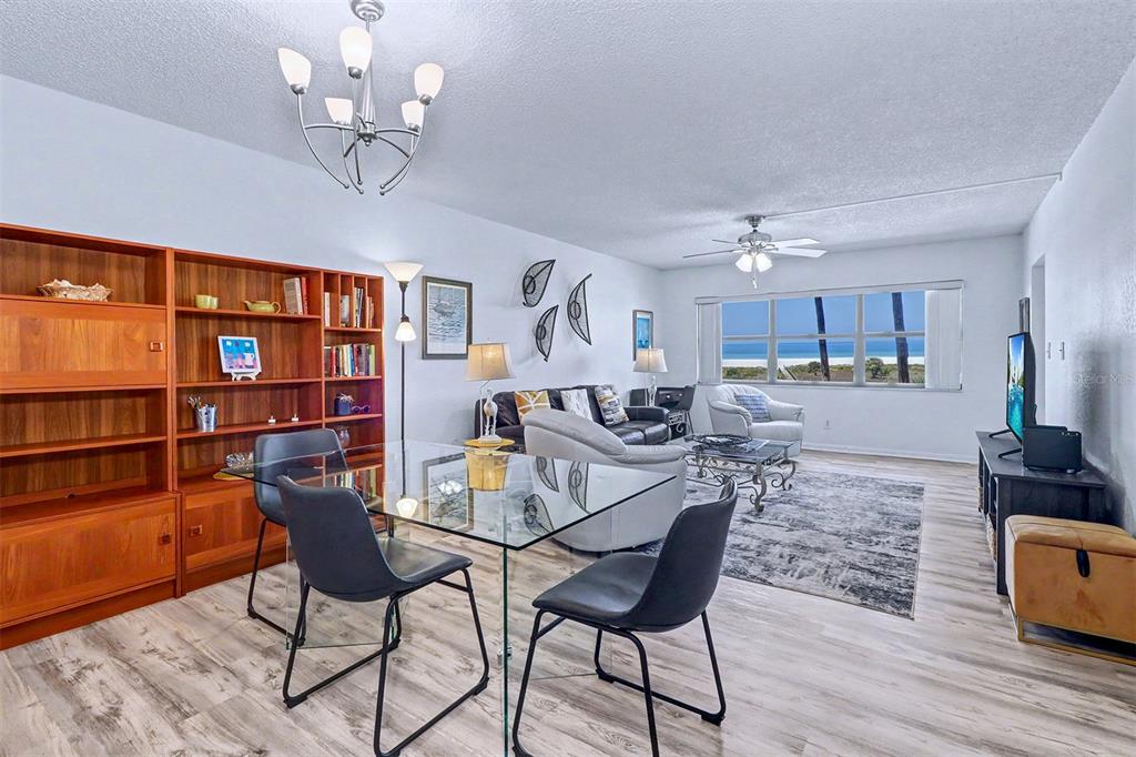 A living and dining area features wood shelving, a glass table, and a beach view — 1230 GULF BOULEVARD UNIT 404, CLEARWATER BEACH, FL